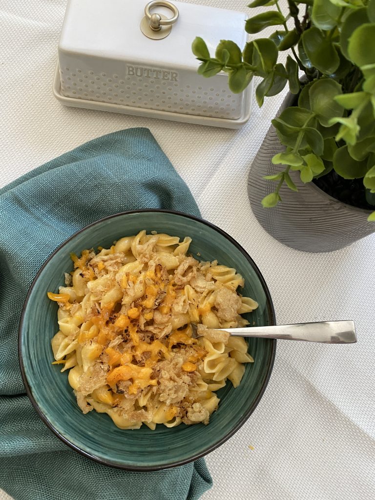Microwave Mac and Cheese Recipe with Crispy Cheese Topping placed beside a butter dish and a house plant.